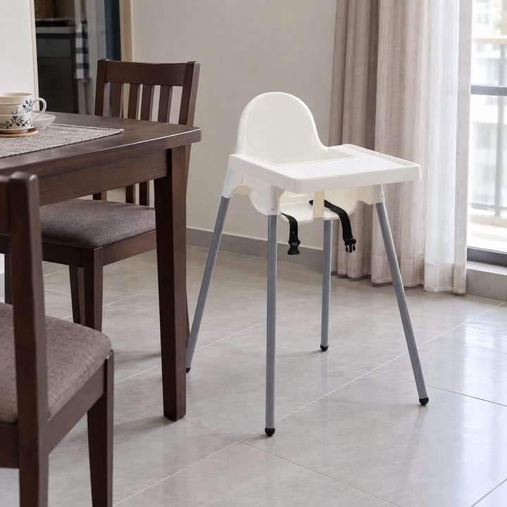 White FCI baby chair with tray beside a Malaysian dining table.