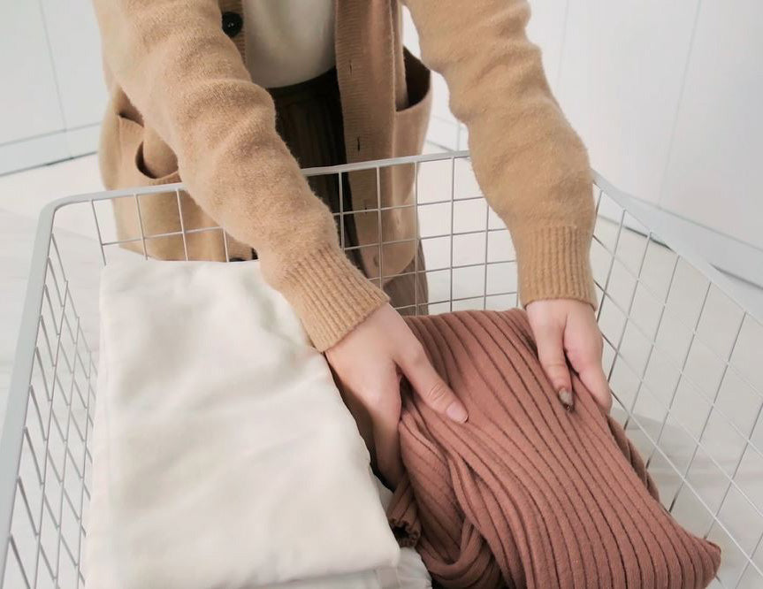 Close-up of folded clothes being organized in a BIANCA Low Storage Cabinet basket
