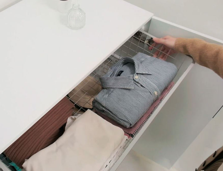 Hand pulling open a BIANCA Low Storage Cabinet drawer with a folded shirt inside